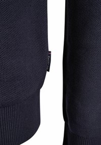 Marineblaues Sweatshirt aus strukturierter Strickware, mit gerippten Bündchen und Saum. Etikett an der Seite sichtbar, akzentuiert mit roten und weißen Streifen.