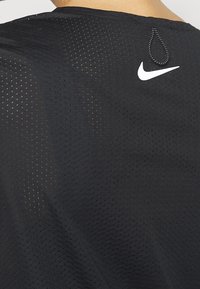 Nike svart mesh-träningsskjorta med perforerad struktur, med en vit logotyp på baksidan och en liten ögla vid halsen.