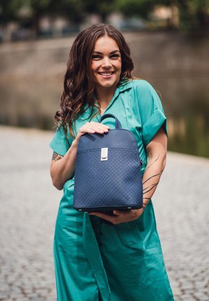 Navy blue leather backpack with textured surface, rectangular shape, top handle, and silver hardware detail.