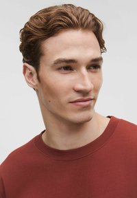 Hanorac bordeaux cu guler dublu, cu o textură fină și un design simplu, purtat de o persoană pe un fundal neutru.