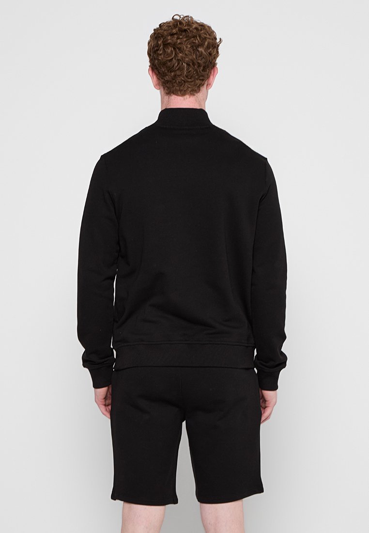 Schwarzer Sweatshirt aus Baumwolle mit gerippten Bündchen und Saum, kombiniert mit passenden Shorts. Schlichtes Design, keine sichtbaren Muster oder Logos.