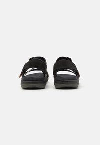 Sorte semskede sandaler med doble justerbare stropper, en polstret fotseng og en teksturert gummisåle for godt grep.