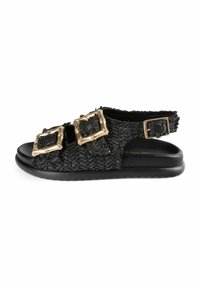 Sandalias planas tejidas negras con dos hebillas cuadradas doradas. Presentan una parte superior texturizada y una suela negra lisa. Diseño de talón abierto con correa ajustable.
