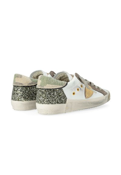 Un paio di sneakers bianche basse con lacci grigi, occhielli dorati, tallone glitterato nero e collo con motivo camouflage verde.