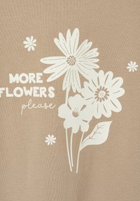 Hellbrauner Stoff mit weißen Blumenmotiven und dem Text "MEHR BLUMEN bitte." Zu den Merkmalen gehören große Gänseblümchen und kleinere Blumen.