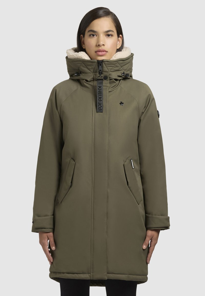 Olijfgroen parka met een bontgevoerde capuchon, rits- en drukknoopsluiting, twee zijzakken en een logo-opdruk op de borst. Zachte textuur.