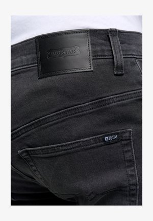 Schwarze Jeans aus Denim mit einer strukturierten Oberfläche und einem auffälligen Aufnäher mit dem "BIG STAR"-Logo. Enthält zwei Gesäßtaschen mit genähten Akzenten.