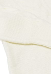 Witte gebreide sweaterstof met een kabelontwerp en ribbelstructuur, met een zachte, comfortabele uitstraling. Close-up van het materiaal.