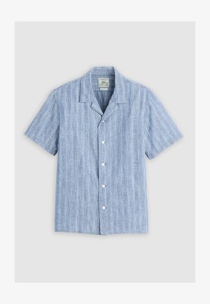 Camisa de manga corta de color azul claro con botones, cuello tipo campestre y un sutil patrón de rayas verticales, extendida sobre un fondo liso.