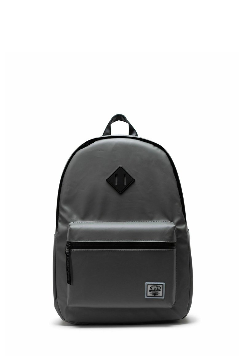 Sac à dos gris au design élégant, fabriqué en matériau durable, avec une poche avant zippée et un patch logo en forme de losange.