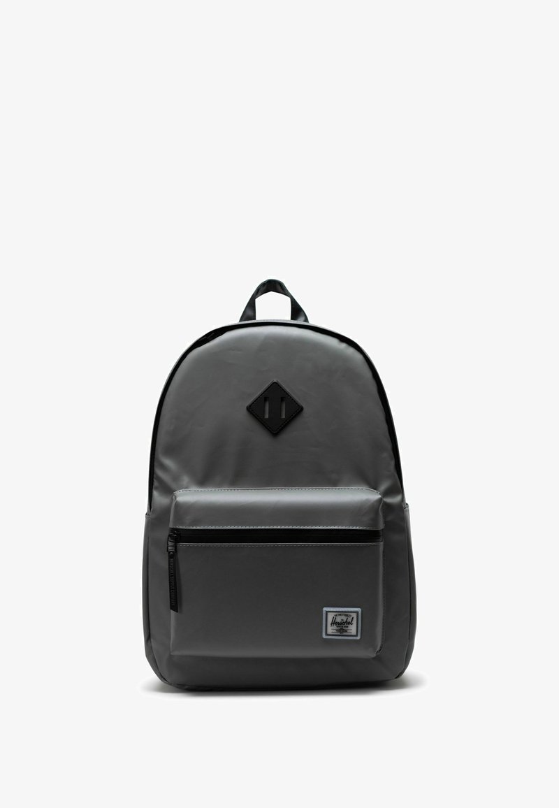 Sac à dos gris au design élégant, fabriqué en matériau durable, avec une poche avant zippée et un patch logo en forme de losange.