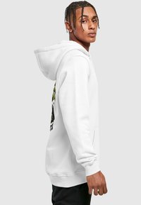 Sudadera blanca con un bolsillo frontal, que presenta un diseño gráfico en negro y verde. Textura suave, puños y dobladillo acanalados.