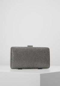 Pochette rectangulaire en tissu argenté, surface texturée avec un fermoir métallique. Design minimaliste, bords lisses et sans motifs apparents.