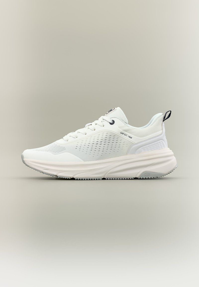 Λευκό αθλητικό παπούτσι με πλευρές από υφασμάτινο πλέγμα με υφή, χοντρή σόλα, μαύρη θηλιά στη φτέρνα και το κείμενο «GAP EST. 1969» τυπωμένο κοντά στα κορδόνια.