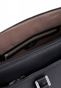 Sac à main en cuir noir avec une surface texturée, doté d'une poche zippée et d'un intérieur lisse, doublé de beige. Accents en métal argenté visibles.