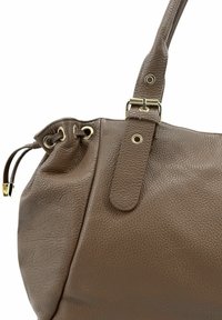 Sac à main en cuir marron avec une finition texturée, doté d'une fermeture supérieure à cordon et d'accents de quincaillerie dorée.