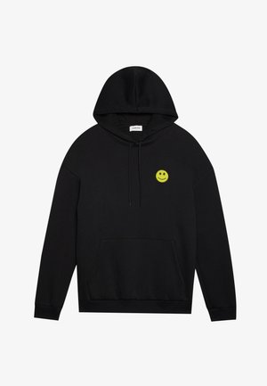 Zwarte hoodie met een voorzak, voorzien van een klein groen glimlachend gezichtembleem op de linker borst en een geribde zoom en mouwen.