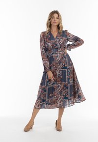 Rochie cu mâneci lungi, tip wrap, în albastru închis, cu modele paisley și buline. Material fluid, lungime midi și detaliu cu talie elastică.