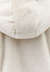 Kurtka z kapturem z futra syntetycznego w jasnym beżu, charakteryzująca się miękką fakturą i gładkim wykończeniem. Kaptur jest puszysty z delikatnym połyskiem.