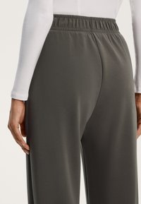 Höga, mörkgrå joggers med elastisk midja. Slät tyg med avslappnad passform och sidofickor.