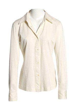 Chemise crème à manches longues avec boutons et col pointu, présentée sur un mannequin sans tête sur fond blanc.