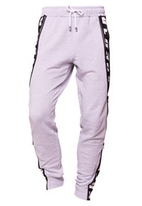 Grå svettbyxor med dragsko i midjan, med svarta sidofickor och ett kontrasterande svart rand med vit text längs sidorna.