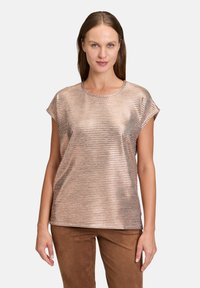 Haut court à manches courtes en rose doré métallique avec une texture côtelée et un col rond, associé à un pantalon en suède marron.