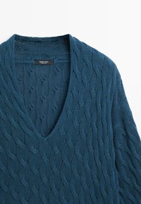 Pull bleu en maille torsadée avec col en V profond et manches longues, présentant un motif tressé texturé et une étiquette de marque Massimo Dutti.