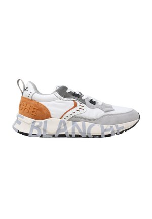 Sneaker bianca e grigia con tallone in suede marrone e grande testo stampato sulla suola, con lacci neri e bianchi.