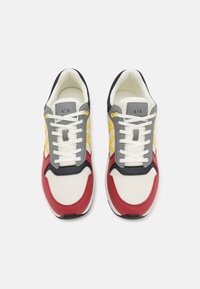 Red, grey, and yellow sneaker with a mesh and synthetic upper, featuring a padded tongue, white laces, and a textured sole.