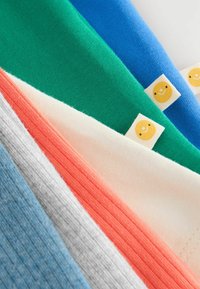 Des morceaux de tissu multicolores avec des rayures vertes, bleues, pêches, crème, grises et bleues, chacun étant attaché avec une étiquette de visage souriant.