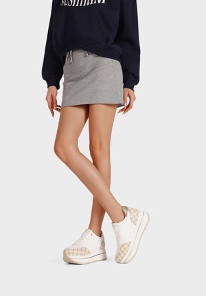 Sneakers bianchi con dettagli beige testurizzati e suola platform, abbinati a una gonna grigia e a una felpa blu marina con vita regolabile.