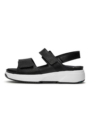 Zwarte sandaal met verstelbare banden, gestructureerde bovenkant en een gevoerde witte zool. Heeft een gesloten achterkant en een rubberen zool voor grip.