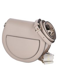 Ljust beige lädercrossbody-väska med en böjd form, en framficka och en spiralformad rem. Utrustad med guldfärgad hårdvara och ett mönstrat remförstärkning.