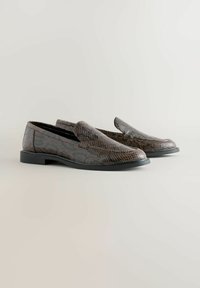 Ruskeat käärmeennahkakuosiset loaferit, joissa on sileä pinta, pyöreä kärki ja kestävä matala musta pohja. Ominaisuuksiin kuuluu minimaalinen ompelu ja helposti puettavat malli.