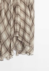 Leichter, fließender Rock in einem beigen und braunen karierten Muster. Verfügt über geschichtete Volants am Saum und eine weiche Textur.