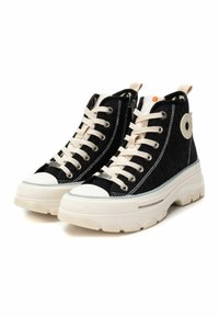 Zapatillas altas hechas de tela negra con cordones blancos, parte superior texturizada y suela gruesa color crema. Presenta un detalle de logo circular.
