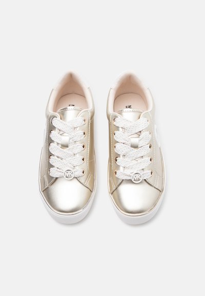 Ζευγάρι από μεταλλικά χρυσά χαμηλά αθλητικά παπούτσια με λευκά κορδόνια και στρογγυλό ασημένιο κρεμαστό λογότυπο MK στα κορδόνια του δεξιού παπουτσιού, σε θέαση από πάνω.