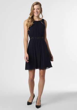 Navy blue sleeveless dress with pleated bodice, fitted waist with beaded detail, and flowing skirt, paired with black heels.