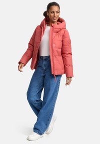 Veste en corail rembourrée avec capuche, dotée d'une fermeture éclair à l'avant, de poignets élastiques et de coutures géométriques ; assortie à un jean large bleu clair.