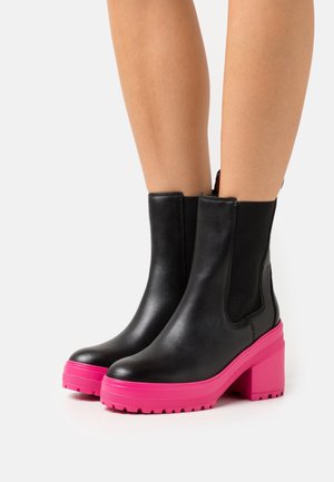 Black leather ankle boots with a chunky pink heel and rubber sole. Elastic side panels for easy wear. Smooth texture with a sleek design.