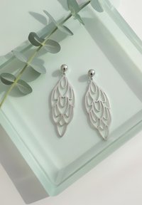 Silverhängen med en lagerbladdesign med utskurna mönster, som visar en jämn yta och glänsande, runda studs.