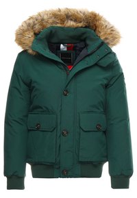 Giacca isolante verde scuro con cappuccio in pelliccia sintetica, chiusura a zip, parte anteriore con bottoni e due tasche frontali con patta piatta. Texture liscia.