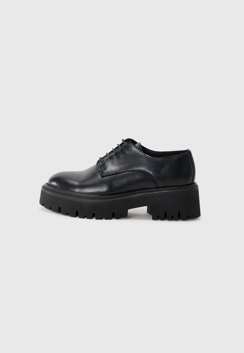 Chaussure noire en cuir à lacets avec une semelle épaisse et robuste et un talon bas, vue de côté sur un fond gris clair uni.