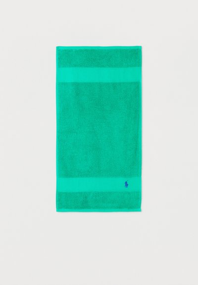 Φωτεινή πετσέτα σε σχήμα ορθογωνίου σε τιρκουάζ χρώμα με υφασμάτινες ταινίες υφής και μικρό κεντημένο μπλε λογότυπο αλόγου κοντά στην κάτω άκρη.