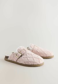 Rosa Kunstpelzslipper mit gepolstertem Muster, verstellbarem Riemen und Gummisohle, mit einem kreisförmigen Schnallendetail.