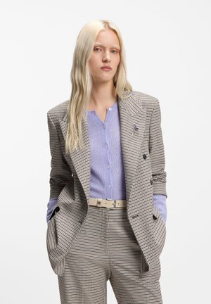 Double-breasted blazer in a brown and cream houndstooth pattern, paired with a light purple button-up top and cream belt. Tailored fit.