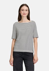 Stribet kortærmet t-shirt i sort og hvid med en bred udskæring, lavet af blødt stof, kombineret med sorte jeans.