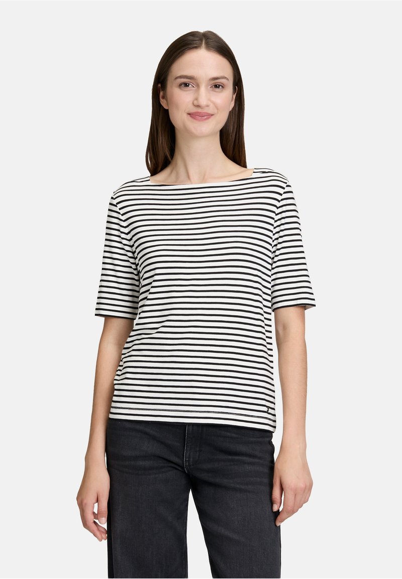 Stribet kortærmet t-shirt i sort og hvid med en bred udskæring, lavet af blødt stof, kombineret med sorte jeans.