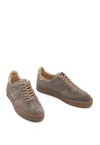 Un paio di sneakers in suede taupe con suole marroni, lacci frontali e accenti in stampa leopardata sui collari del tallone.